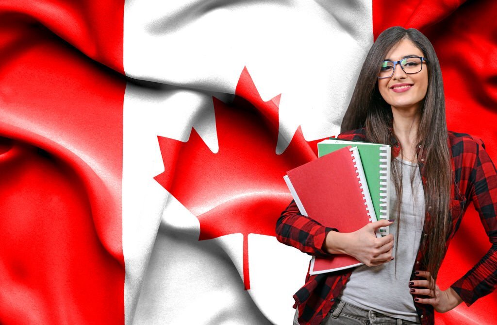 Happy Female Student Holdimg Books Against National Flag Of Canada